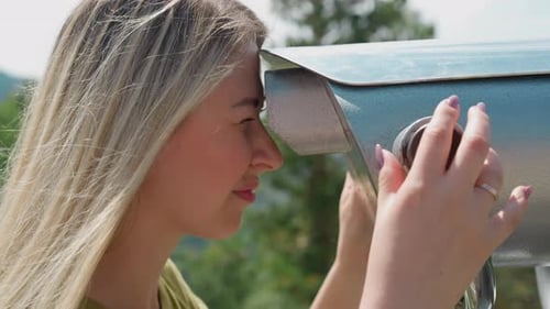 Smiling Woman Turns Wheel Looking in Binoculars at Resort