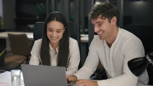 Smiling Colleagues Collaborate on Laptop in Modern Office