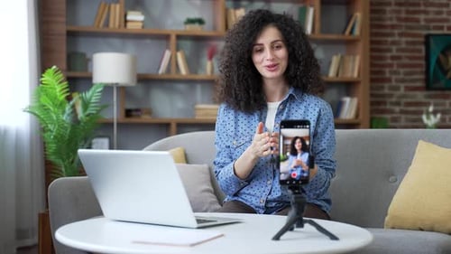 Selbstbewusste Privatlehrerin, die Videoanrufe, Unterricht oder Training mit dem Smartphone auf dem Sofa gibt