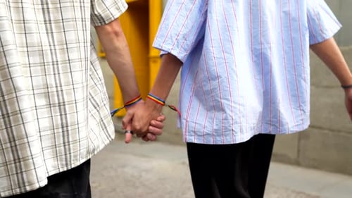 Couple Holds Hands and Walks Down a Cobblestone Street