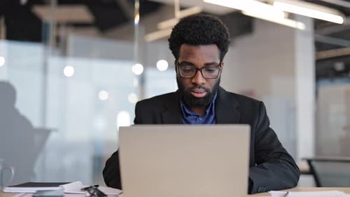 Smiling Successful Businessman Working On His Laptop In A Modern Office