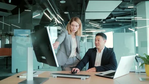 Colleagues Discuss Project at Office Computer