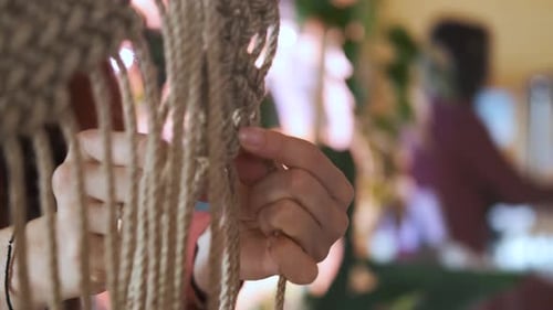 close-up female hands weaving macrame