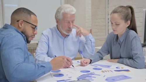 Three Professionals Collaborate at Office Table