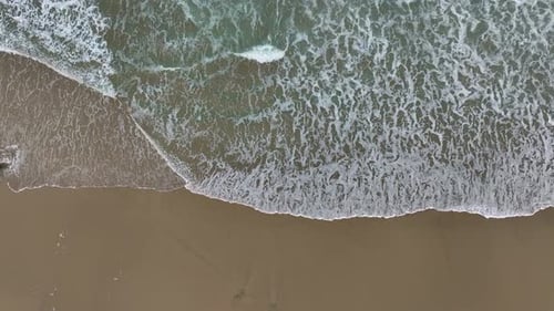 Sea Foamy Water Waves Crashing On Sandy Beach - Aerial Top Down