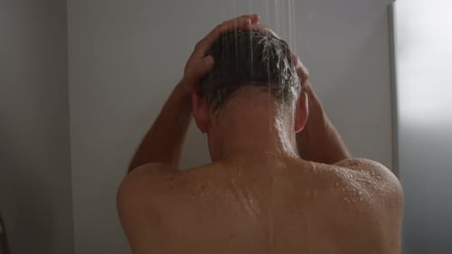 Man Washing Hair Under Shower in Bathroom