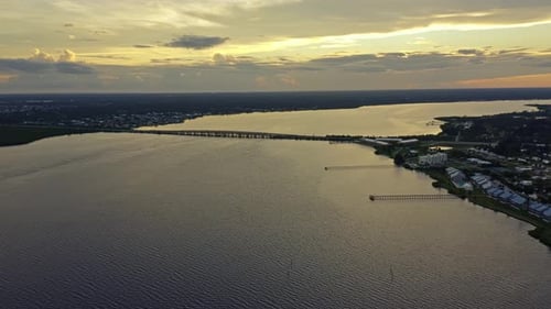 Bridge stretching over wide bay waters under glowing sunset sky