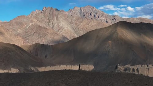 Aerial Drone shot of a man running on the top of the mountain in ladakh.