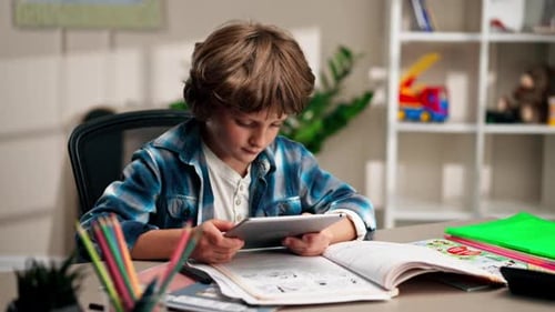 in the Children's Room a Schoolboy in a White Sweater and a Blue Checkered Shirt at a Desk Does