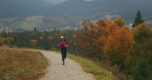 Woman Running on Mountain Trail in Autumn Landscape