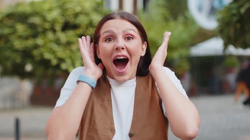 Caucasian Young Surprised Woman Looking at Camera with Big Open Eyes Shocked By Victory on Street