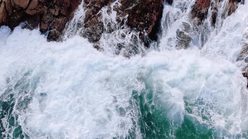 Aerial view of ocean waves breaks on the rocks.