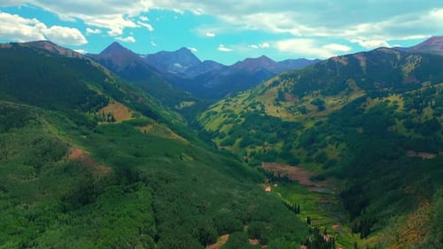 Stunning Aerial View of Lush Green Mountain Valley Under Blue Sky