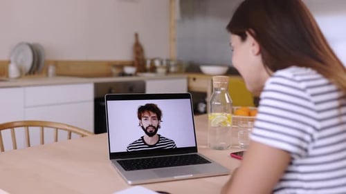 Junge Geschäftsfrau führt einen virtuellen Videoanruf mit einem männlichen Kollegen von zu Hause aus