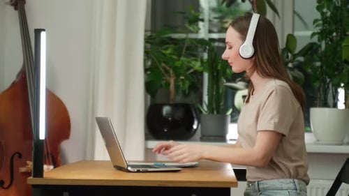 A Female Musician Listens to Music While Composing a Song in a Music Studio