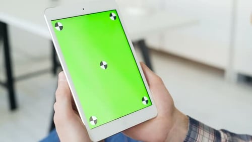 Man Surfing Tablet in Green Screen Lounge