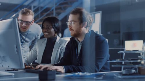 Zwei Elektronikentwicklungsingenieure, die an Computern arbeiten, sprechen mit dem Projektmanager. Das Team von Prof.