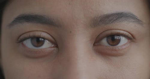 Closeup Slow Motion Portrait of Young Woman's Eyes Looking at Camera with No Expression
