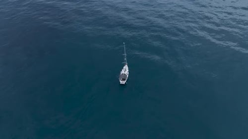 Luftaufnahme einer in der Bucht vor Anker liegenden Segelyacht mit klarem und türkisfarbenem Wasser bei Sonnenuntergang