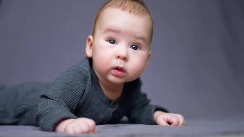 Un tout-petit de quelques mois a appris à garder la tête stable. Un enfant curieux regarde autour de lui allongé sur son lit.