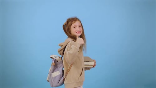 Smiling Child Giving Thumbs Up Holding Books