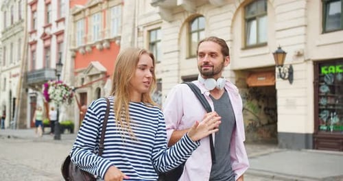 Young Male and Female Students Friends Walking on Street and Having Conversation Woman Telling Guy