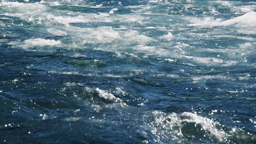 The Dynamic River Water Surface is Adorned with Swirling Waves and Intriguing Bubbles That Mesmerize