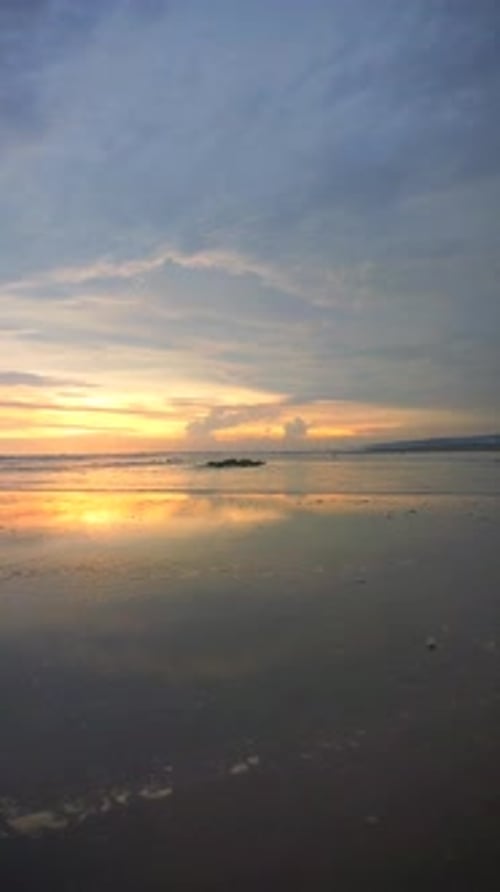 vertical video of beautiful views of the sunset on the beach with small waves, natural panoramas