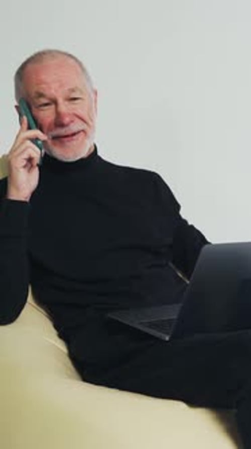 Senior Man Talking on Smartphone with Laptop