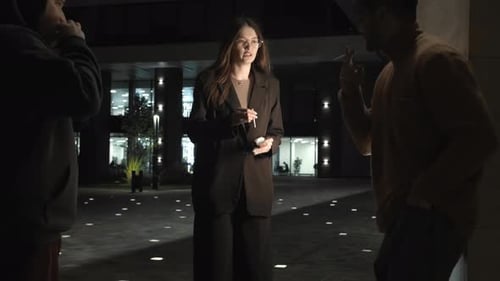 Young Woman is Seen Smoking in the Designated Smoking Area with Her Work Colleagues Engaging in