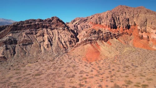 Aerial view drone flying over scenic red rocky mountains landscape with a clear blue sky.