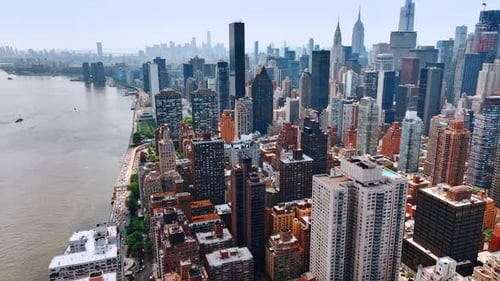 Flying above densely built waterfront of East River in New York on sunny day.