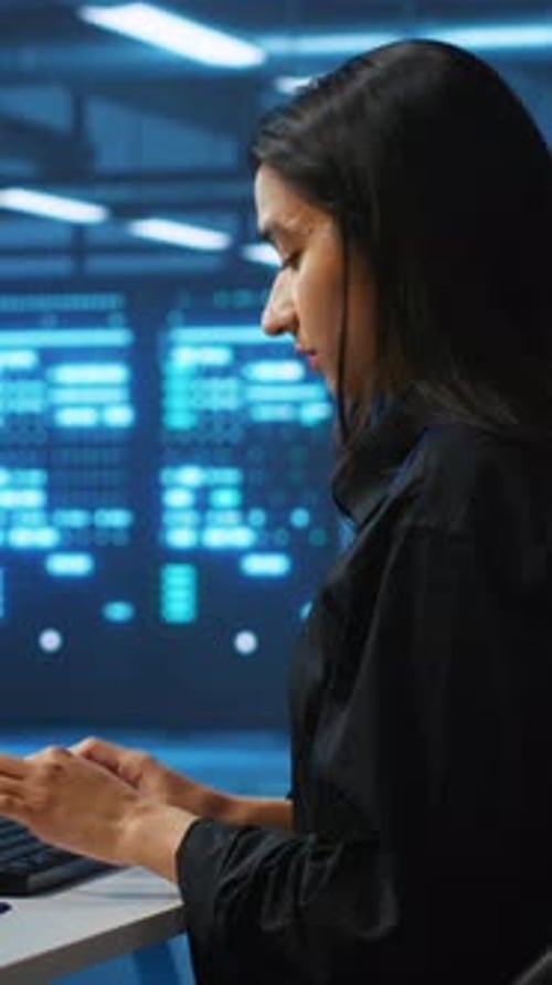 Woman Coding in Server Room with Blue Lights