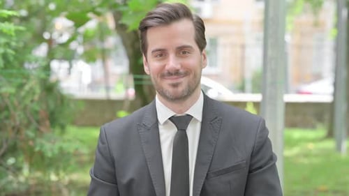 Portrait extérieur d'un jeune homme d'affaires souriant regardant la caméra