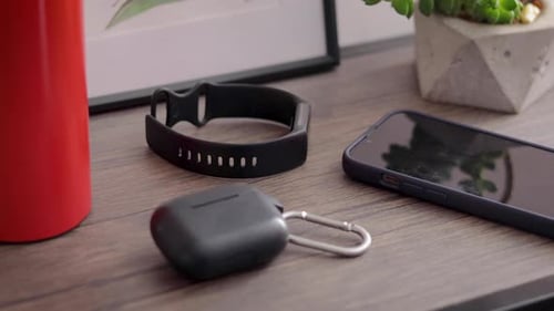 Close up of man taking his cell phone, earphones, smartwatch and water bottle from a table decorated