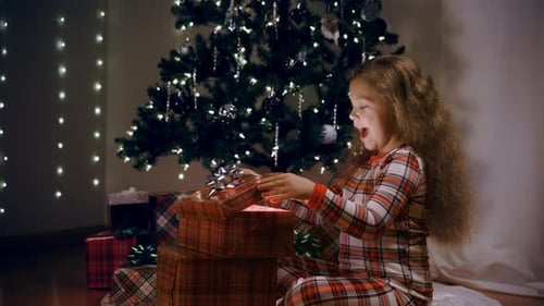 A Girl Opens a Box in a Room Decorated for Christmas Tree Emotions From a Christmas Gift Wide View