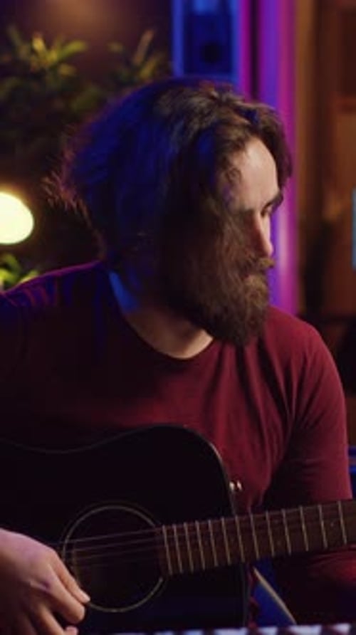 Vertikales Video: Junger Mann, Songwriter, spielt Gitarre und kreiert Musik
