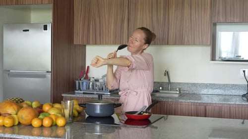 Woman Dancing and Singing in the Kitchen with Ladle