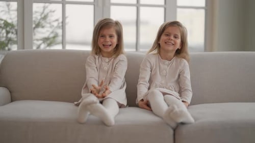 Two Adorable Girls Smiling on Couch