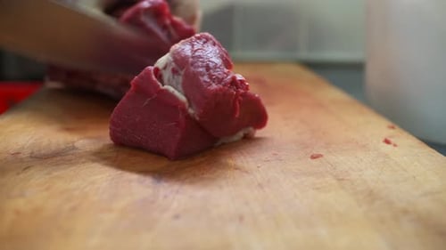 Close up of Raw Meat Being Cut on Board
