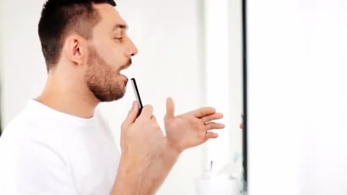 Man Combs Beard in Bright Bathroom