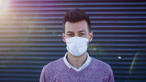 Young businessman in face mask stands against dark city background
