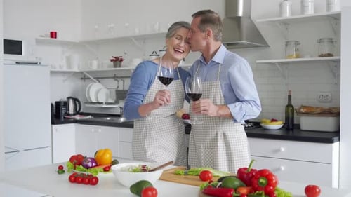 Senior Couple Cooking, Chatting, and Drinking Wine Together