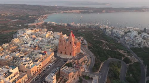 An aerial view of the Mellieha Parish Church in Malta with its red dome and twin bell towers. The