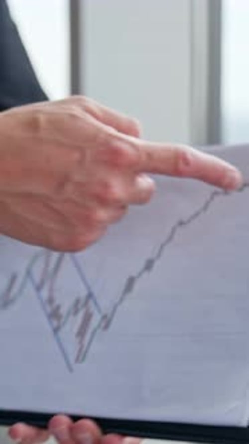 Male hand following the graph printed on the paper.