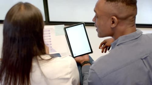 Discussing project, colleagues using tablet and reviewing documents in office, copy space