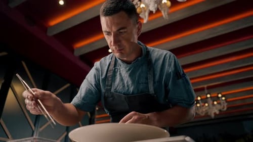 The chef of the Italian restaurant decorates the dish, lays out the ingredients with tongs