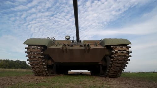 Military Army Tank Moving Across Grassy Hillside