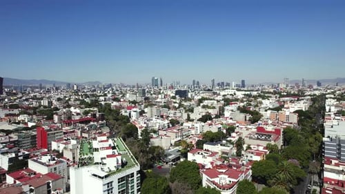 Aerial view of Mexico City, the shadow of an airplane is seen passing through the buildings.