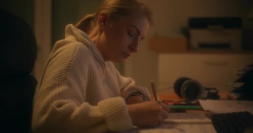 Woman Writing Notes In Office While Working Late At Night